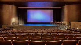 Empty auditorium with all lights on. Visible scrren in the center of stage.